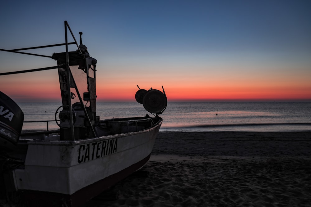 white and black boat on beach during sunset