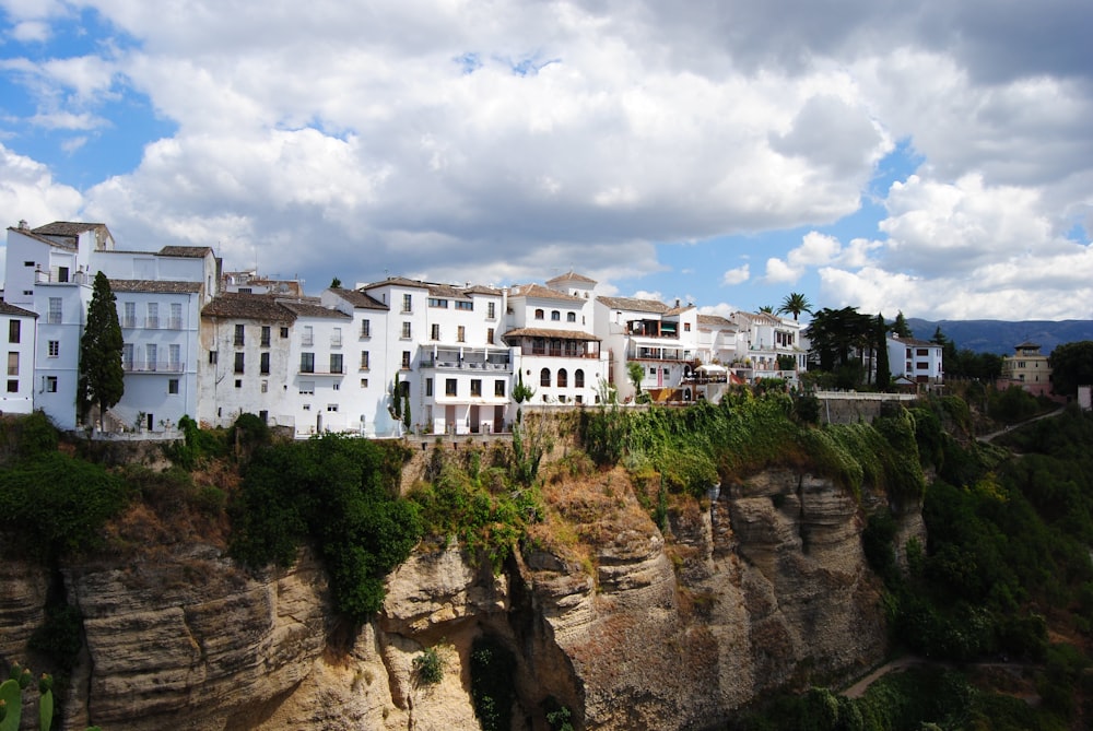 white concrete building on brown rocky mountain under white clouds and blue sky during daytime