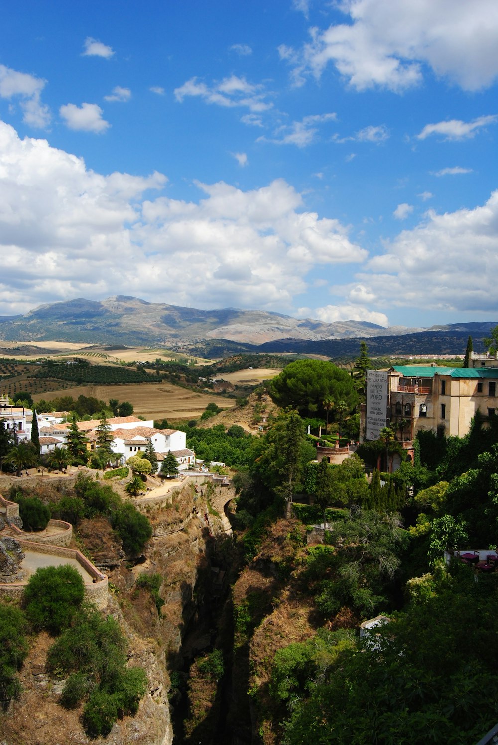 white and brown concrete buildings near green trees under white clouds and blue sky during daytime