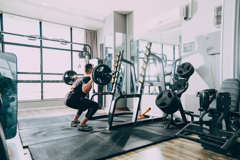 mulher na camisa preta e jeans azul sentado no equipamento de exercício preto