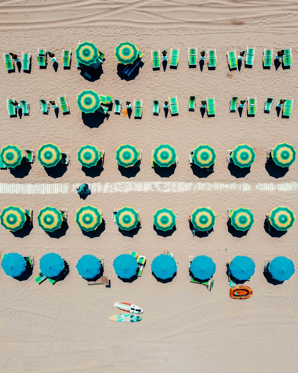 people on beach with blue and white umbrellas