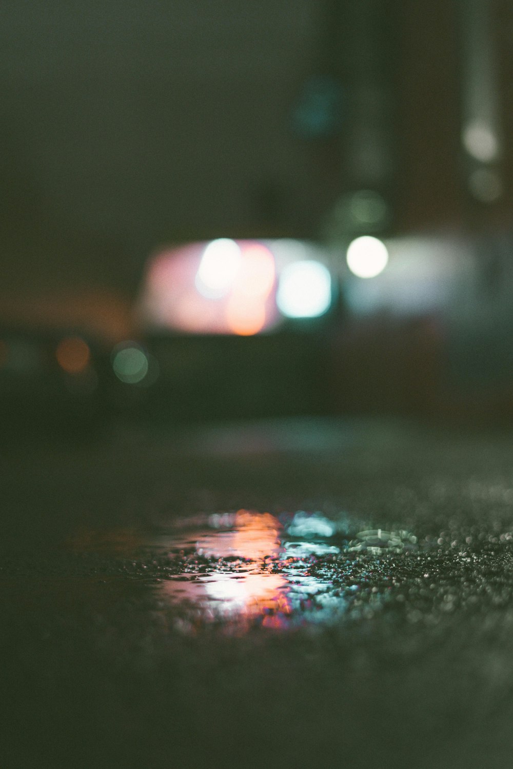 water droplets on black asphalt road during night time