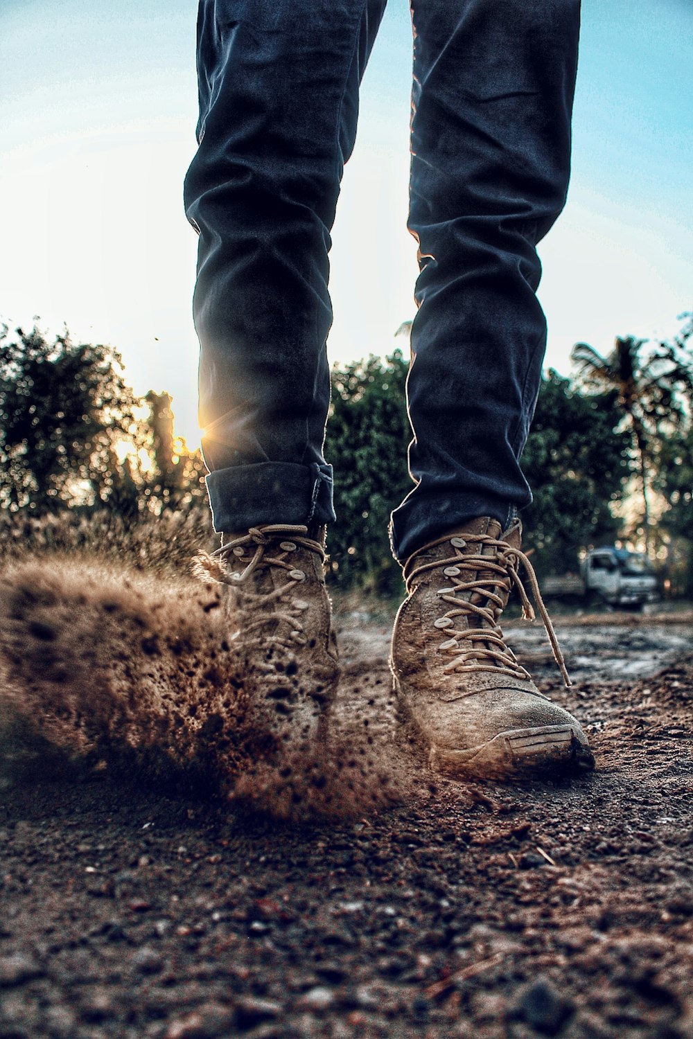 person in blue denim jeans and brown boots standing on brown soil