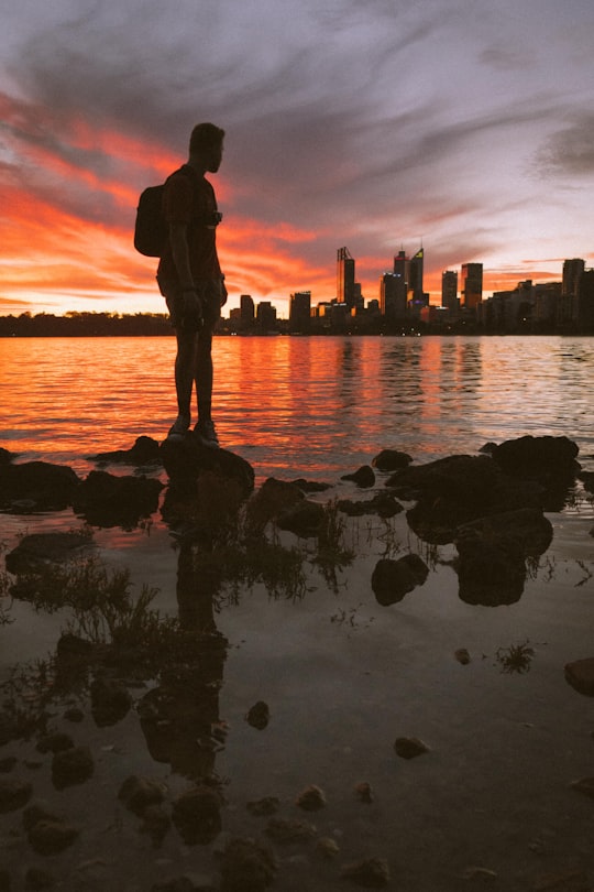 silhouette of man standing on rock near body of water during sunset in Perth WA Australia