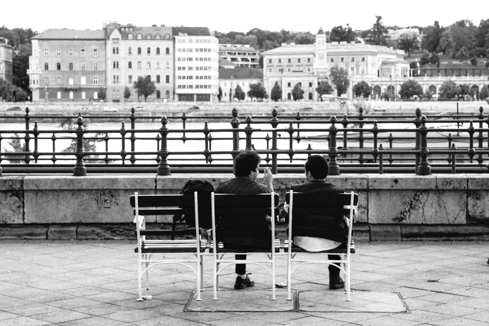 grayscale photo of 2 men sitting on chair