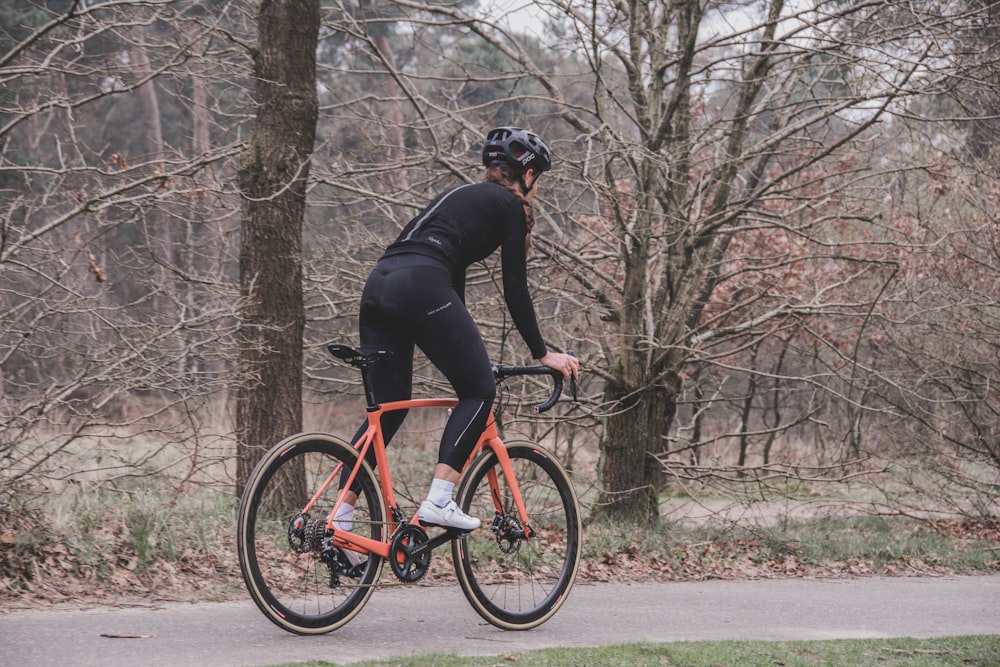 man in black jacket riding red bicycle