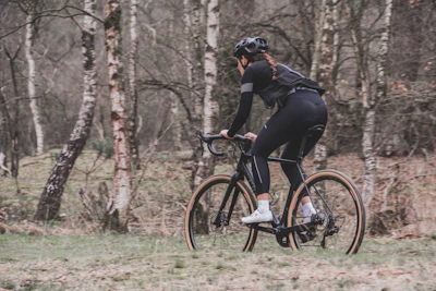 man in black jacket riding on black bicycle on forest during daytime