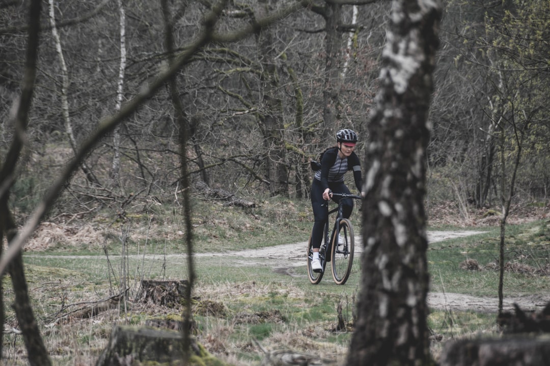 man in black jacket riding bicycle on green grass field during daytime