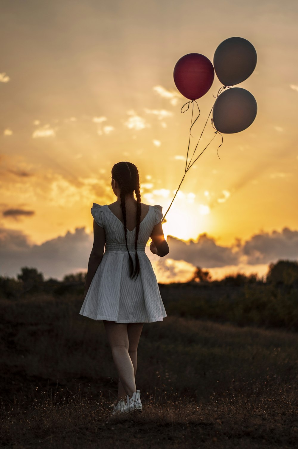 woman in white dress holding balloons