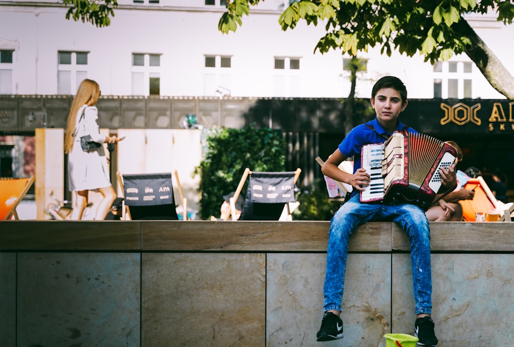 man in blue and white crew neck t-shirt and blue denim jeans sitting on brown