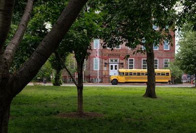 A bright green mini school bus parked outside a cheerful elementary school on a sunny morning.