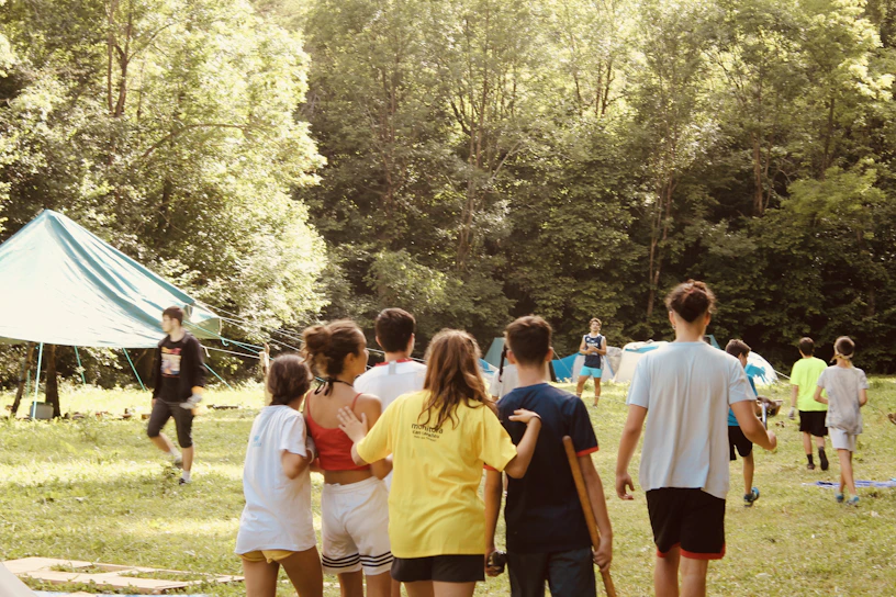 A group of diverse students engaged in a lively outdoor leadership workshop, surrounded by nature.