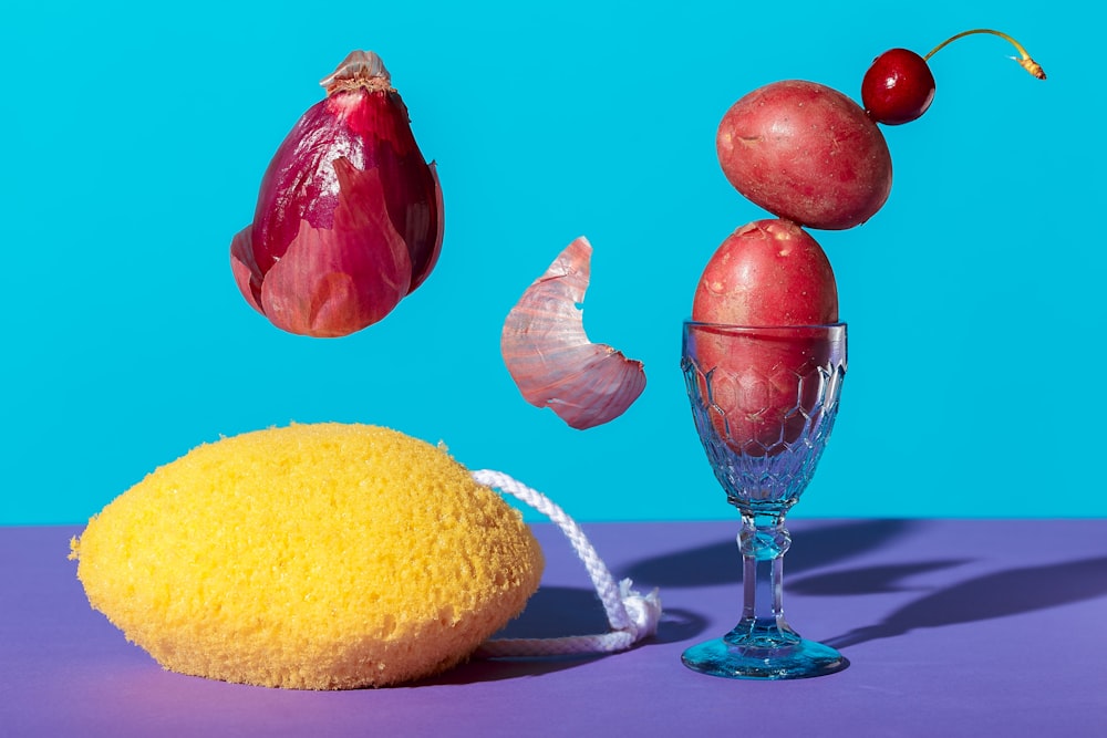 red and yellow fruit beside clear glass vase