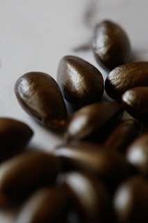 Close-up of golden jojoba seeds resting on a smooth ivory stone surface