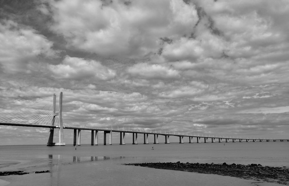 grayscale photo of bridge over the sea