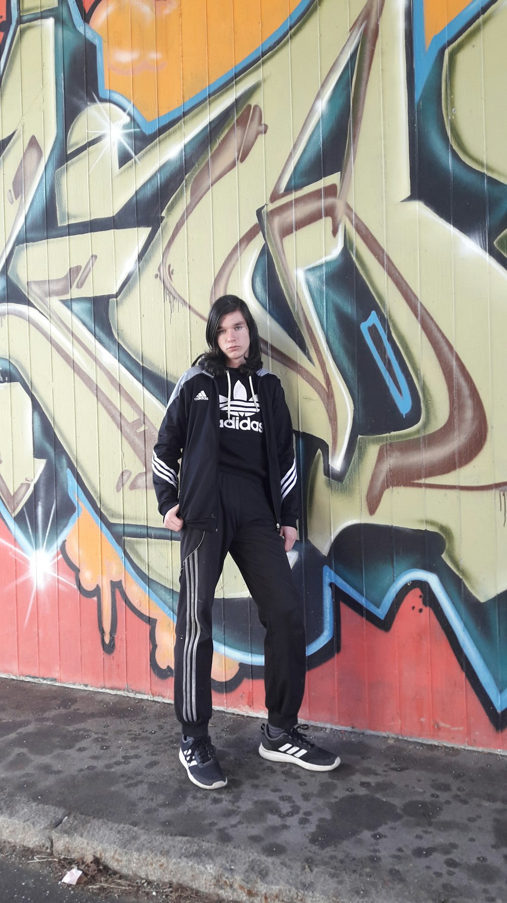 woman in black jacket standing beside wall