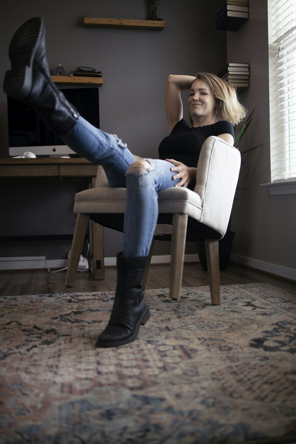 woman in black shirt and blue denim jeans sitting on white chair