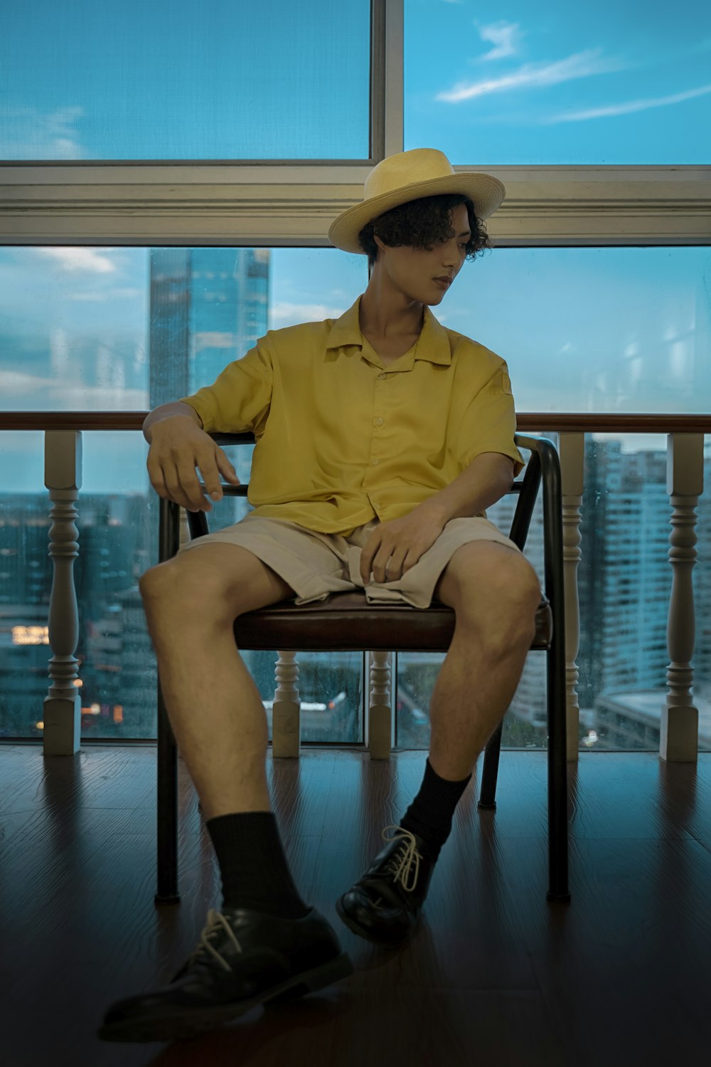 man in yellow dress shirt and black pants sitting on brown wooden chair