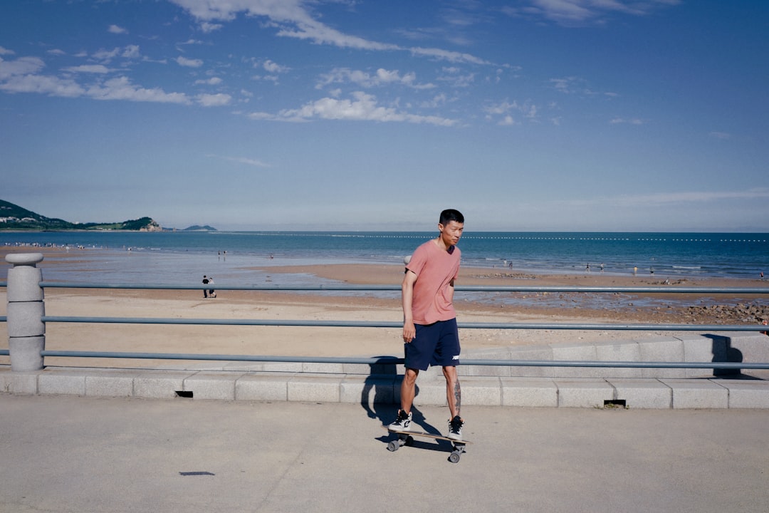 man in white shorts and black nike shoes standing on gray concrete floor near sea during