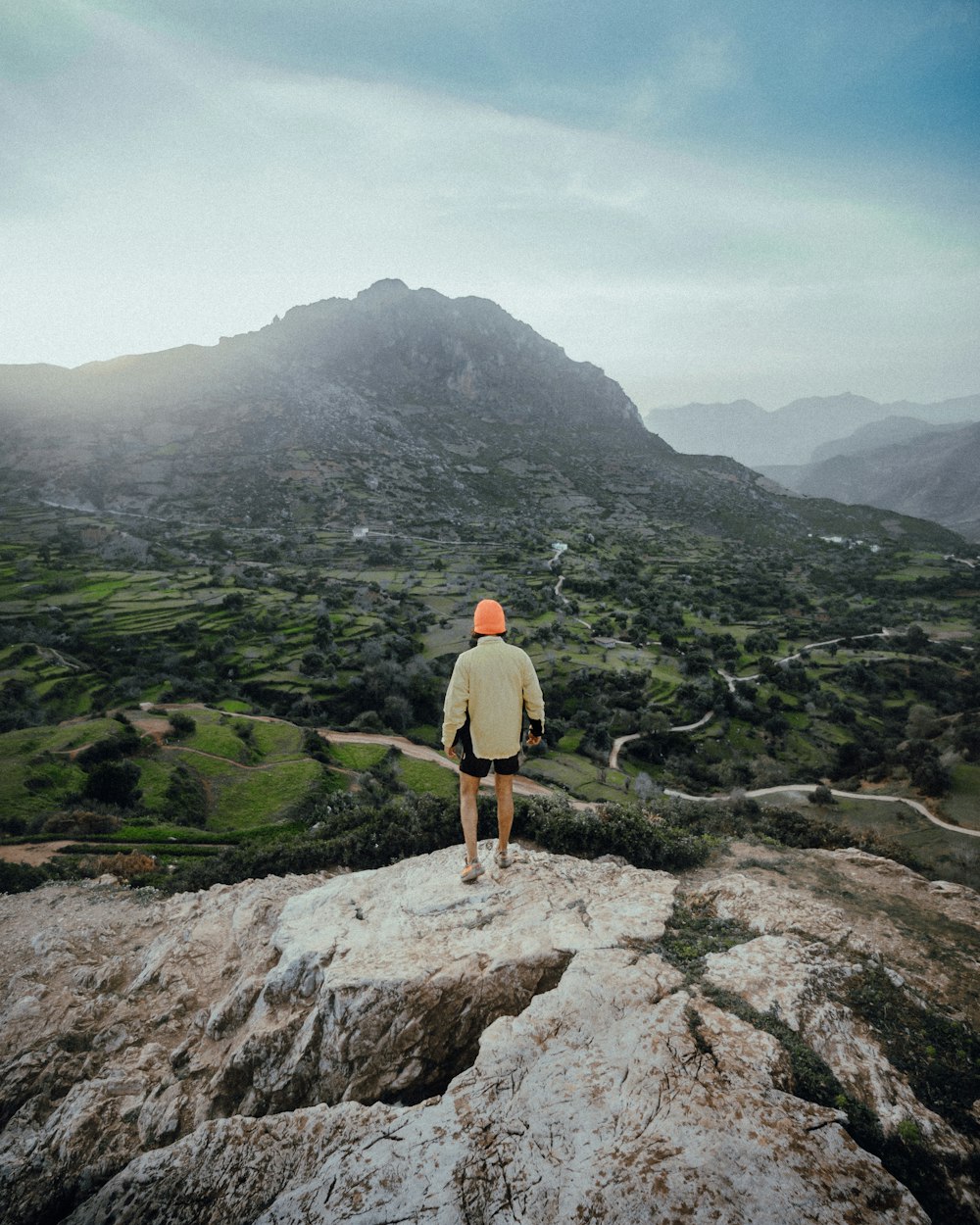 man in brown shorts standing on rock mountain during daytime