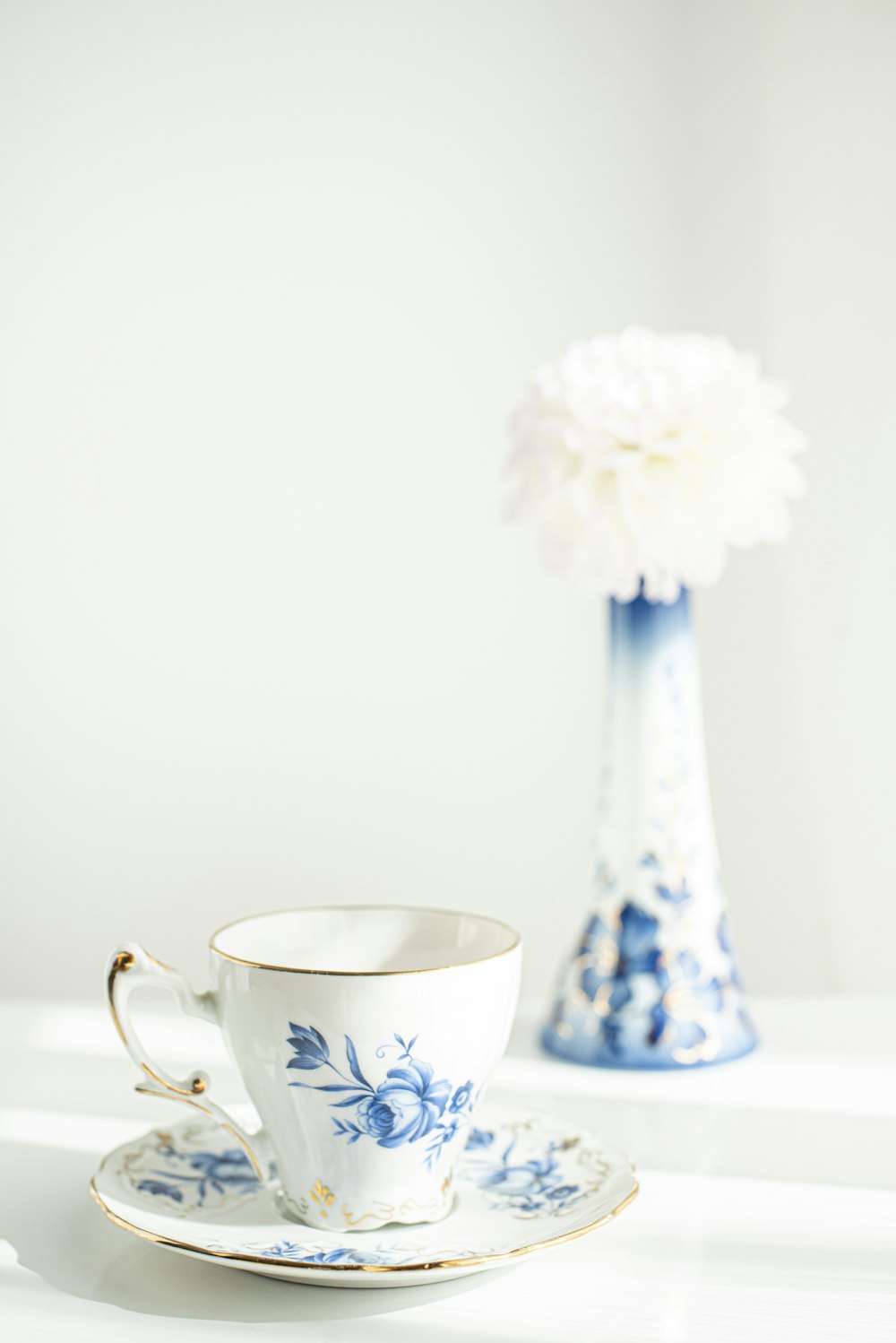 weiße und blaue florale Keramik-Teetasse mit weißer Blume