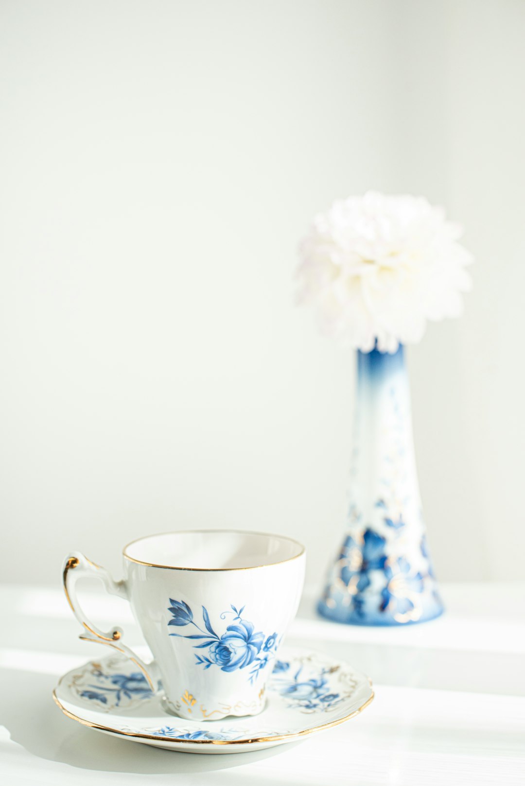 white and blue floral ceramic teacup with white flower