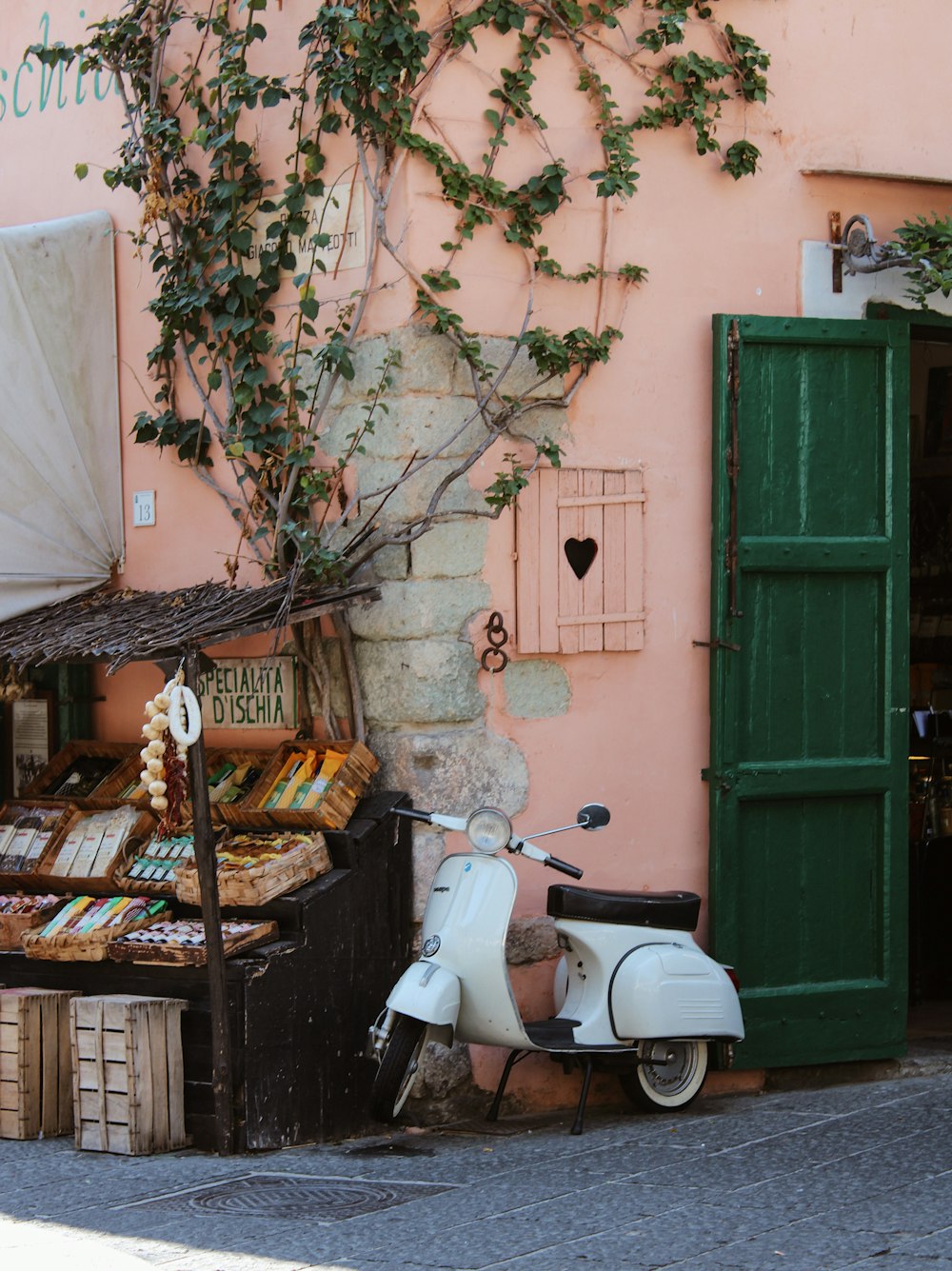 white motor scooter parked beside green wooden door