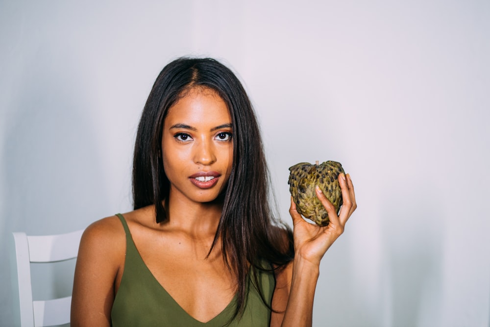 woman in green tank top holding green and brown turtle