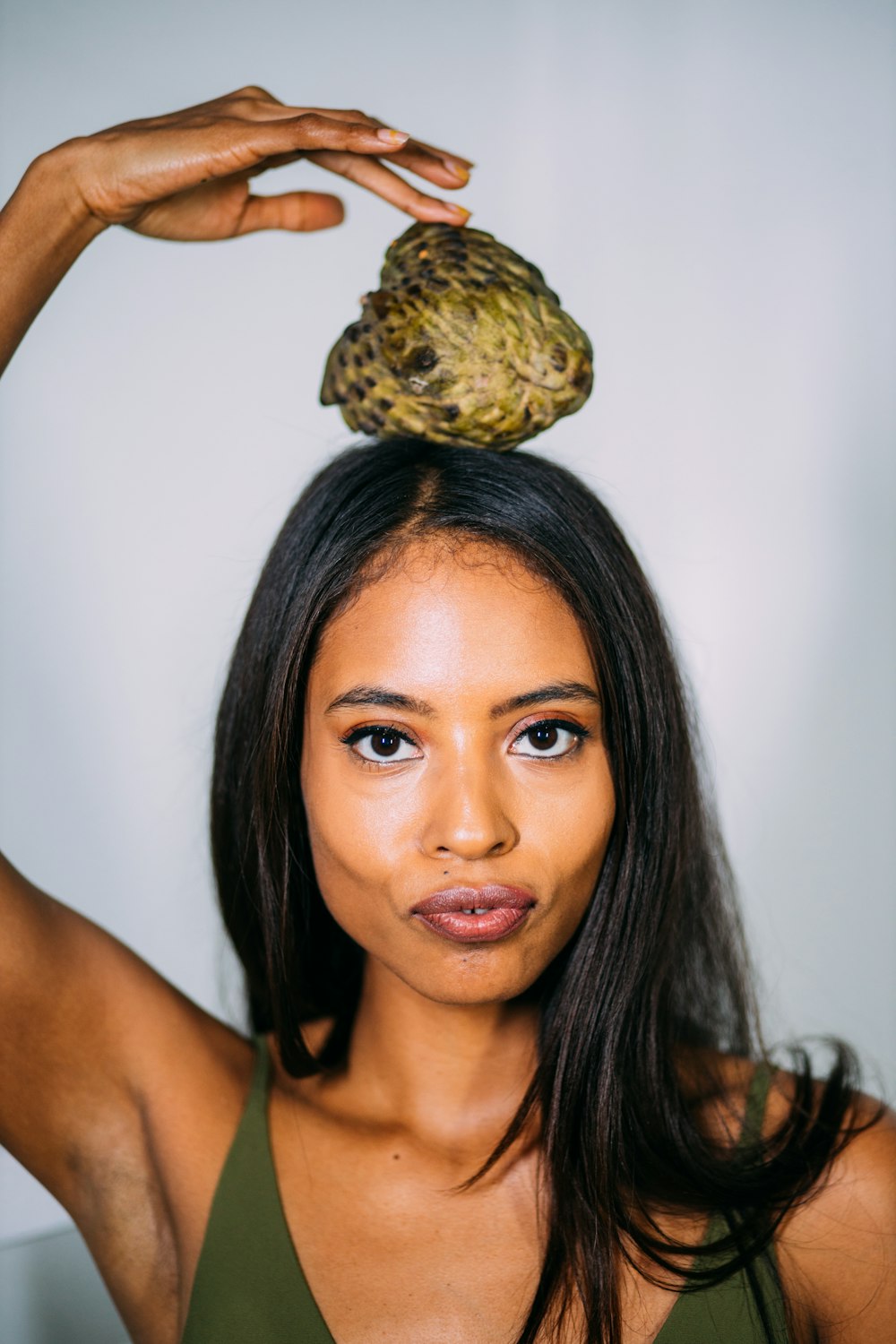 woman holding green and brown fruit