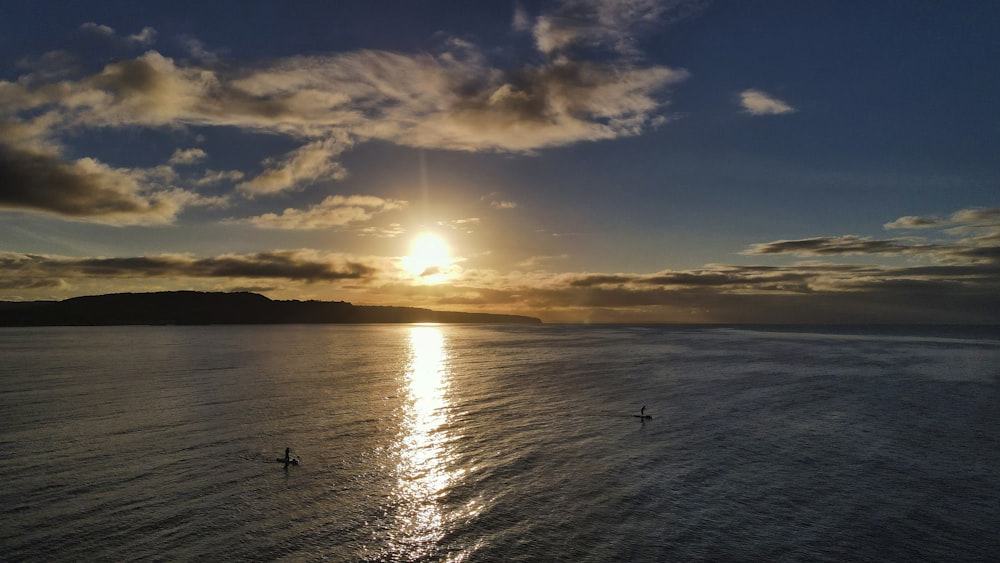 silhueta das pessoas na praia durante o pôr do sol