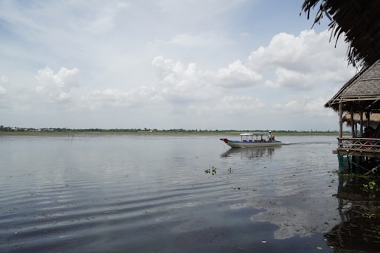 white and green boat on water under white clouds during daytime in Tonle Bati Cambodia