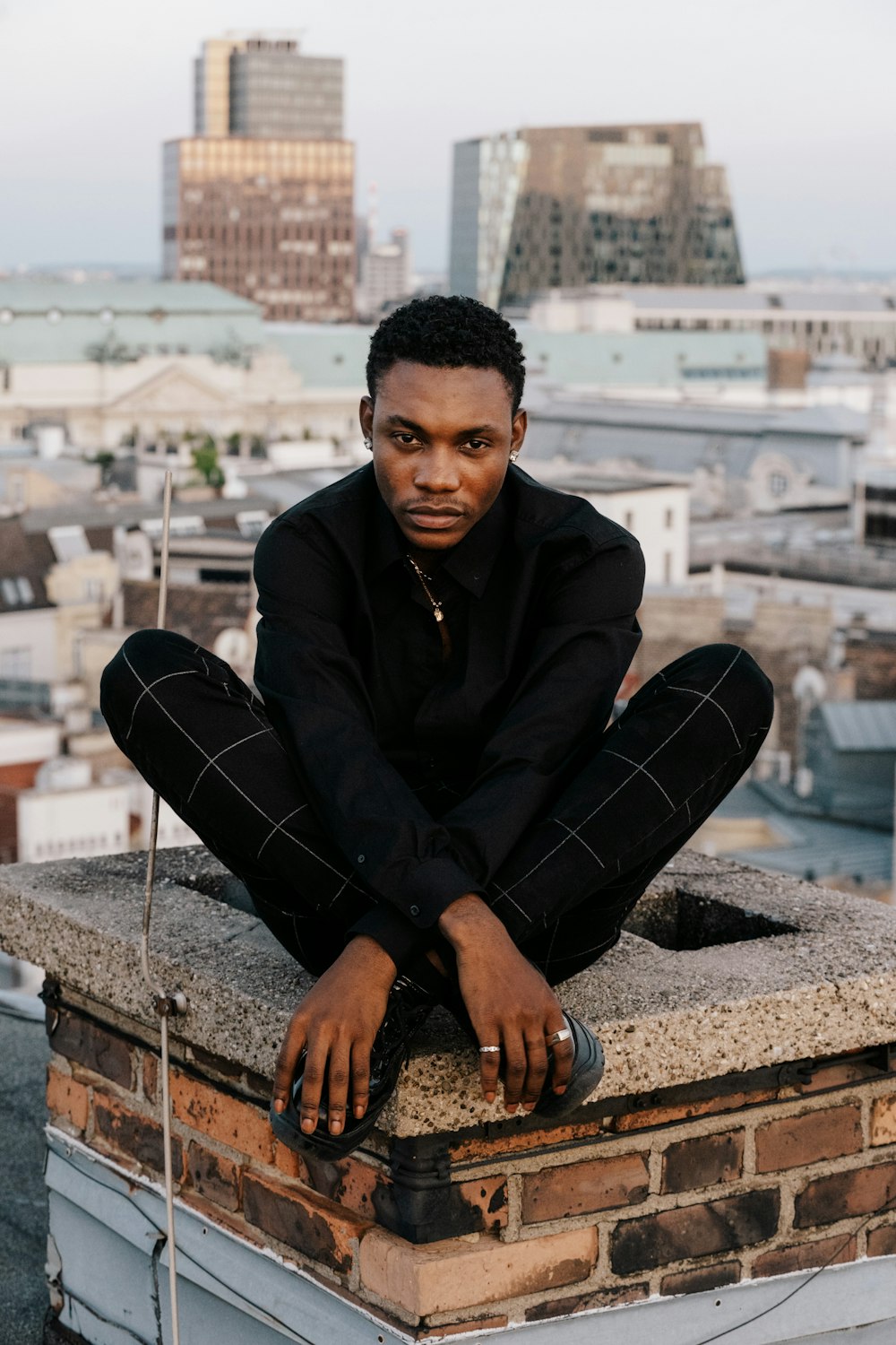 man in black jacket and black pants sitting on brown concrete bench during daytime