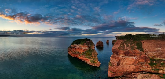 brown rock formation on body of water under blue sky in Ladram Bay United Kingdom