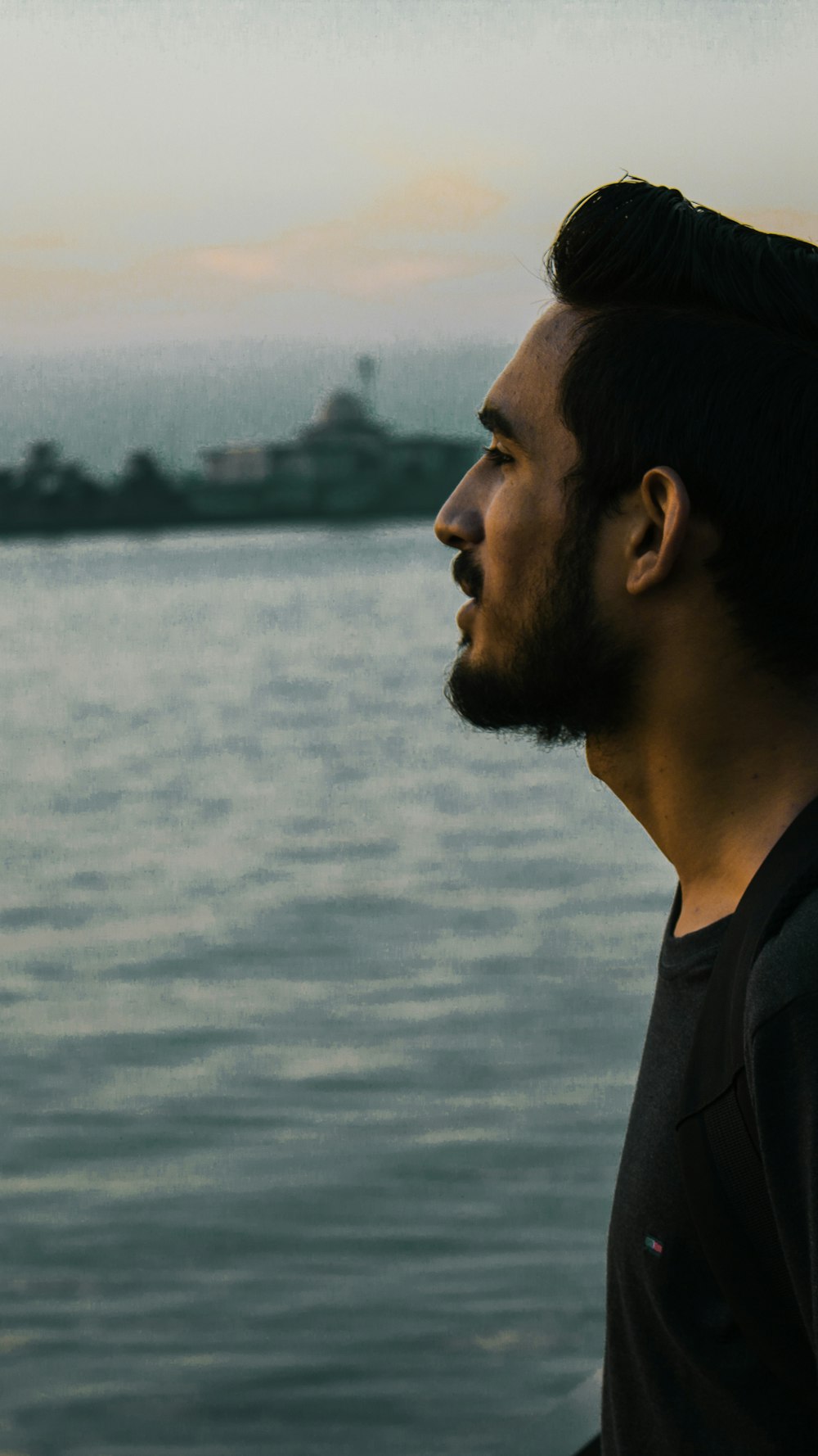 man in black hoodie looking at the sea during daytime