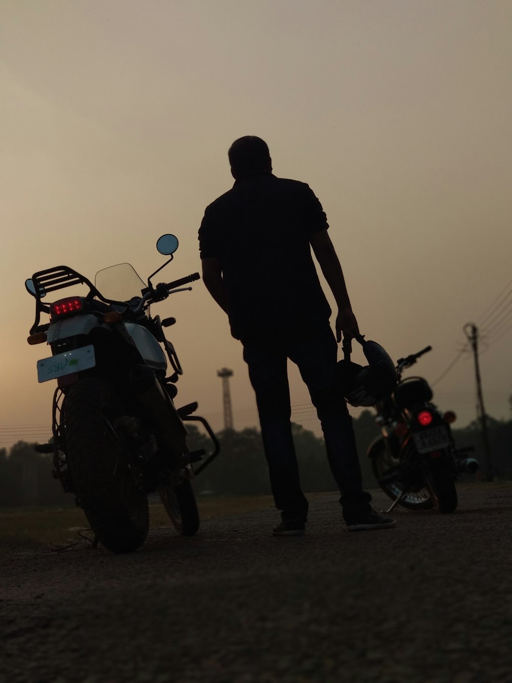 silhouette of man and woman standing beside red and black motorcycle during sunset