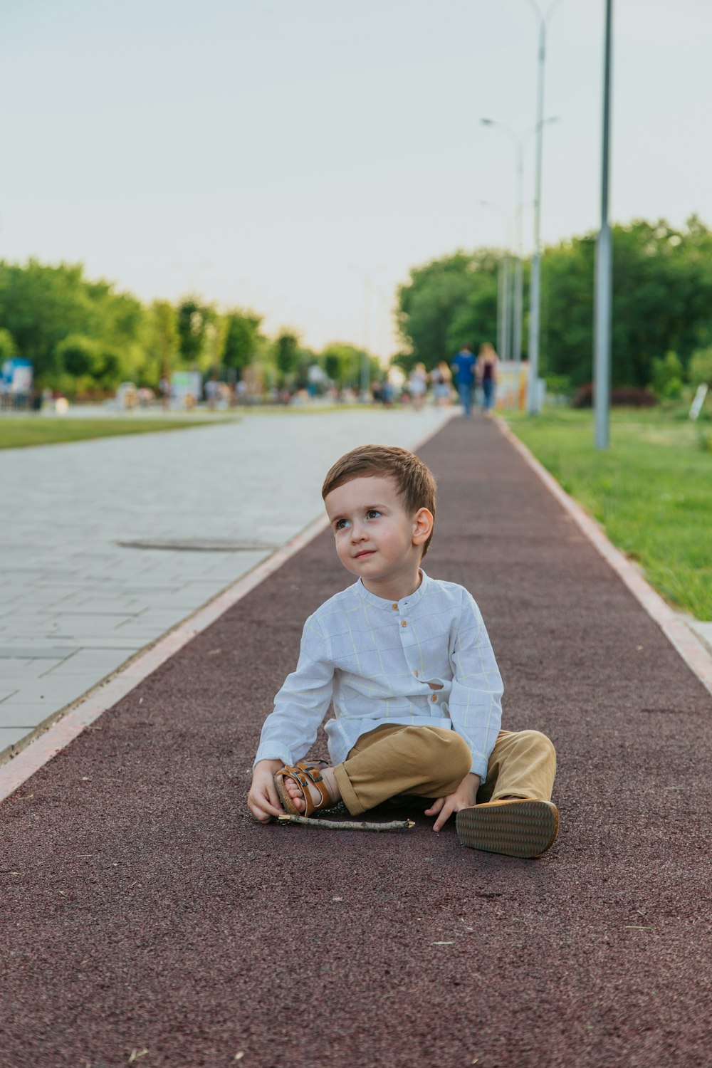 boy in white long sleeve shirt and brown pants sitting on concrete pathway  during daytime photo – Free Person Image on Unsplash