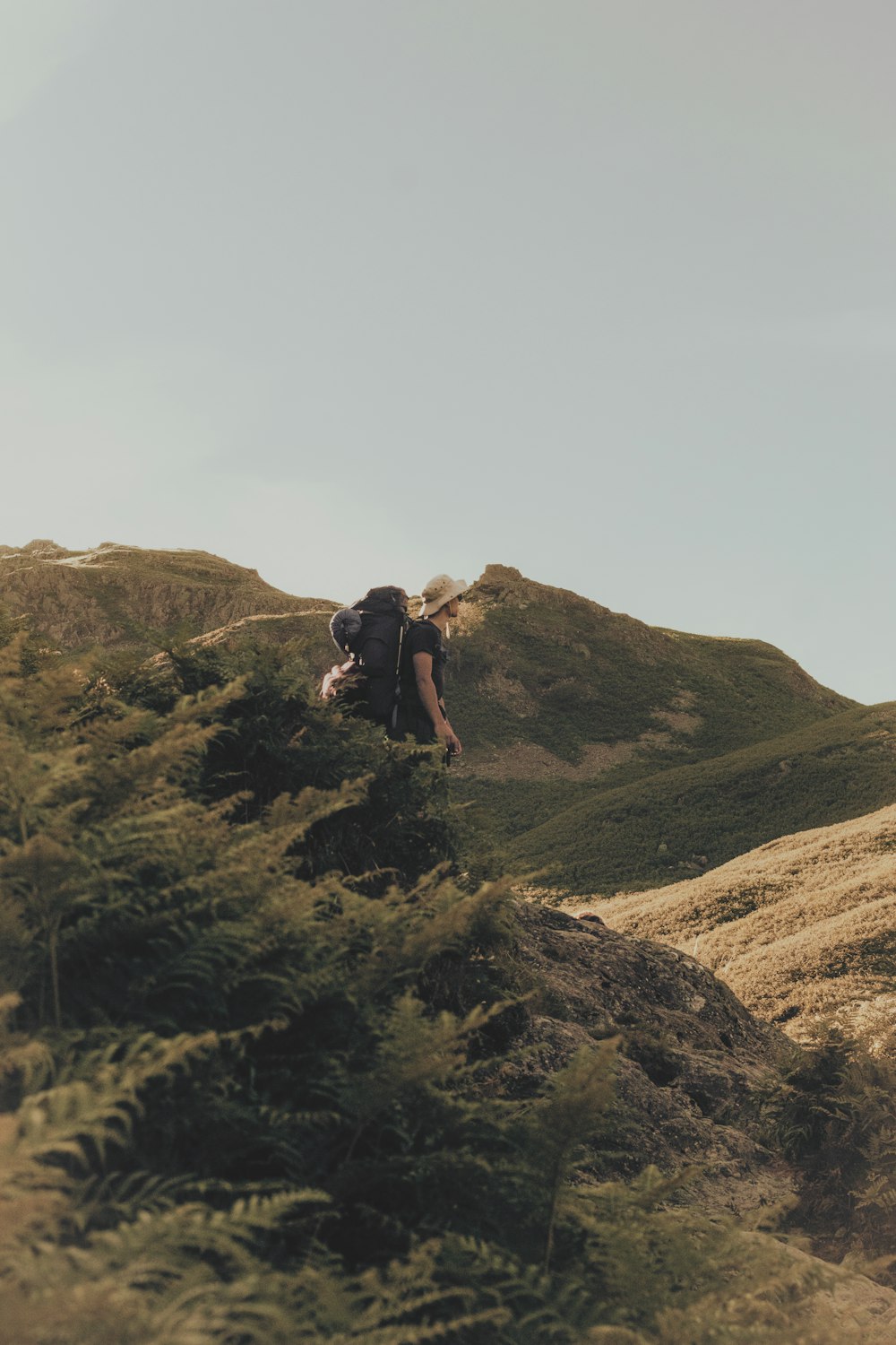 Uomo in maglietta nera e pantaloncini neri in piedi sulla collina marrone durante il giorno