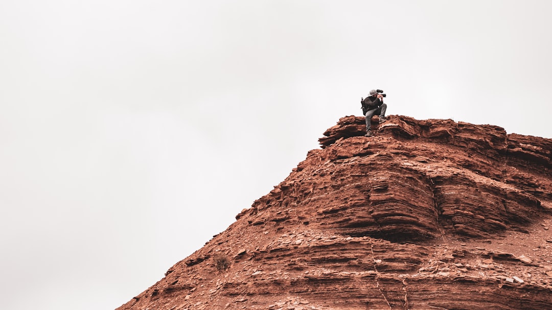 2 men sitting on brown rock formation during daytime