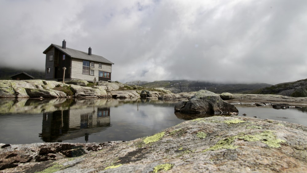 brown and white house beside river under cloudy sky during daytime