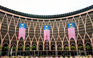 Malaysian treasury building in Putrajaya with Malaysian flag with green trees