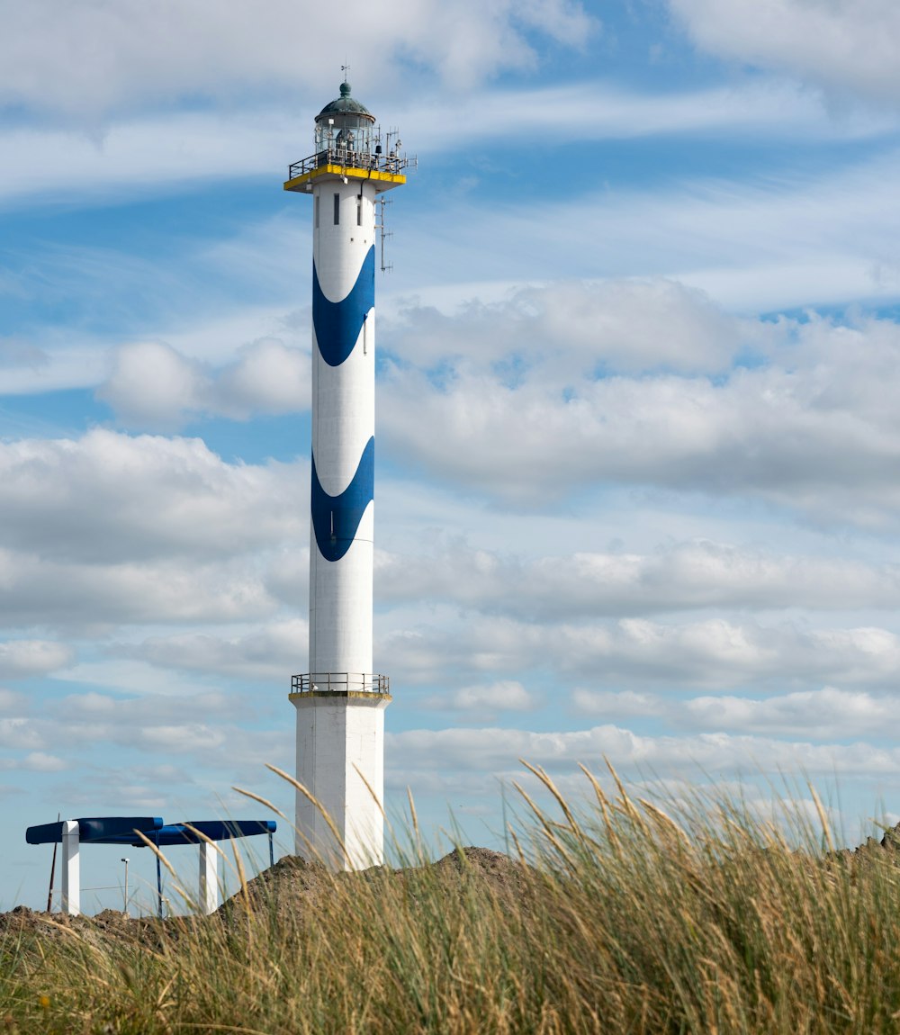 farol branco e azul sob nuvens brancas e céu azul durante o dia