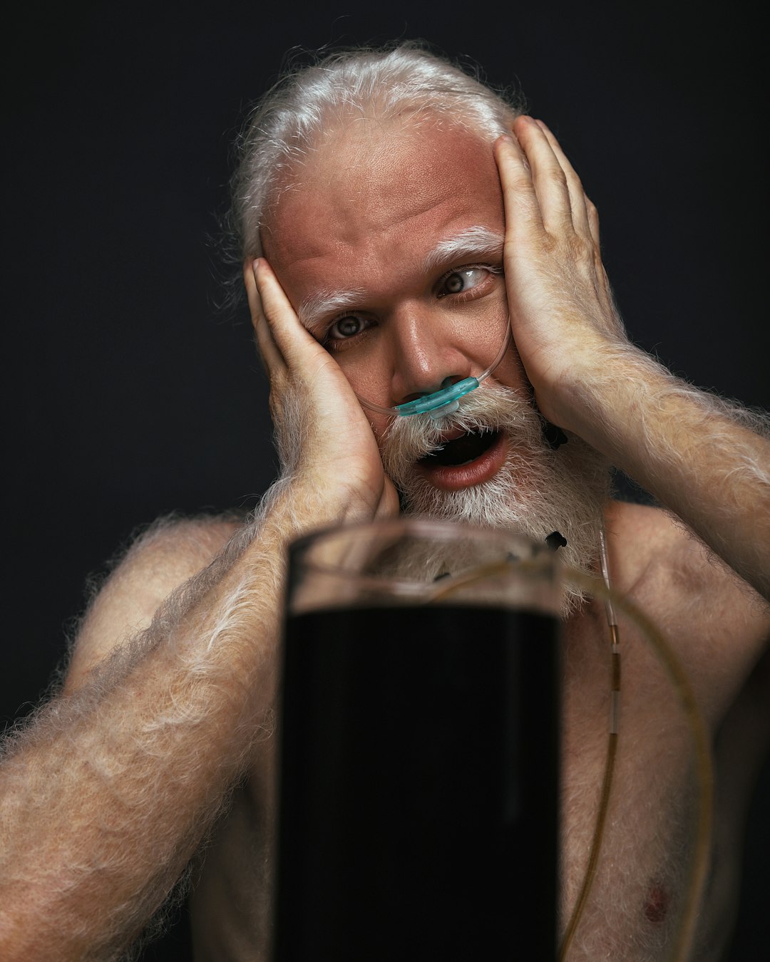 man holding clear drinking glass with black liquid