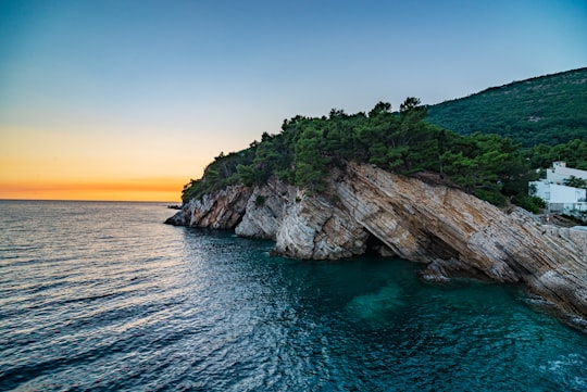 brown and green rock formation on blue sea under blue sky during daytime in Petrovac Montenegro