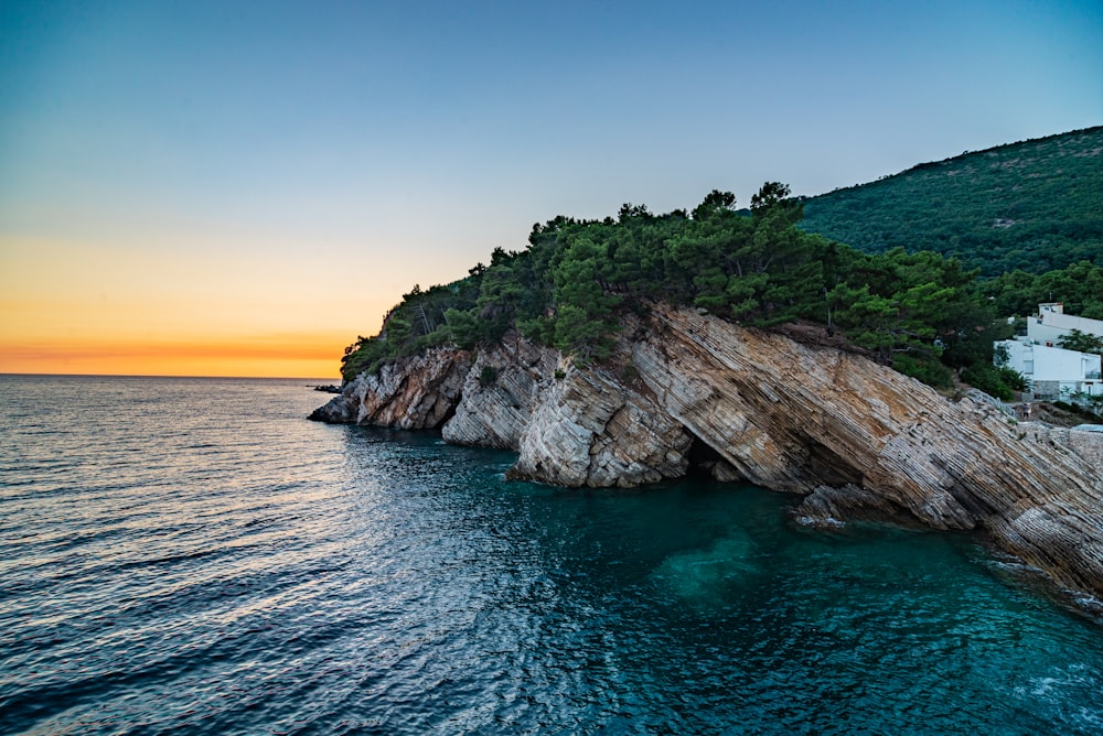 brown and green rock formation on blue sea under blue sky during daytime