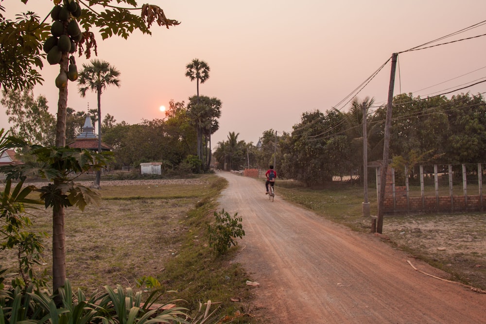 person in red shirt walking on road during daytime