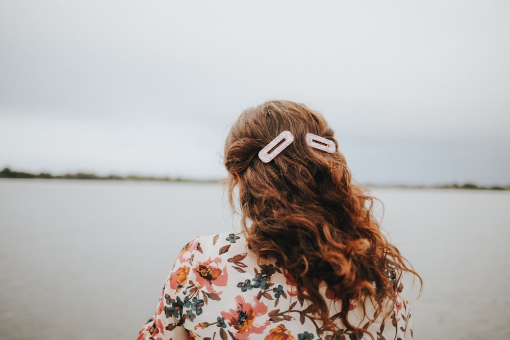 woman in white red and green floral shirt with white and brown hair tie
