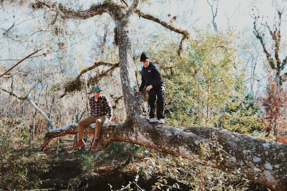 2 women standing on brown tree trunk during daytime