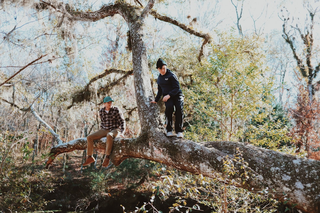 2 women standing on brown tree trunk during daytime