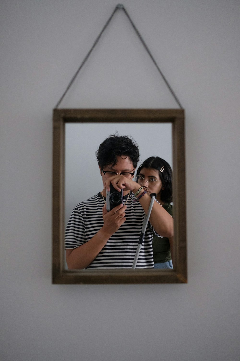 woman in white and black stripe shirt taking photo in front of mirror