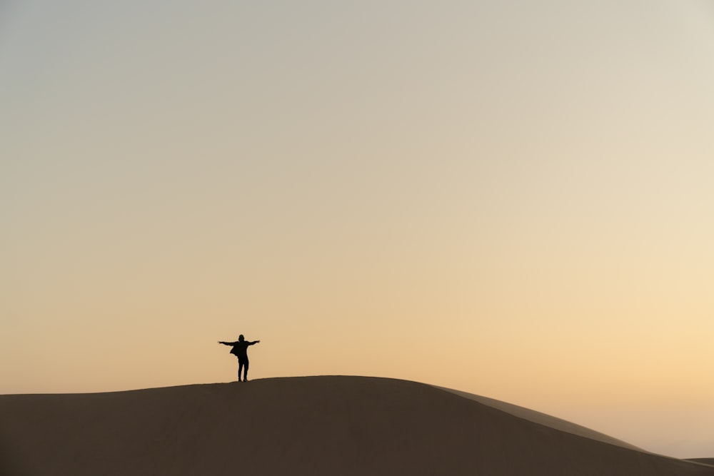 a person standing on top of a sand dune